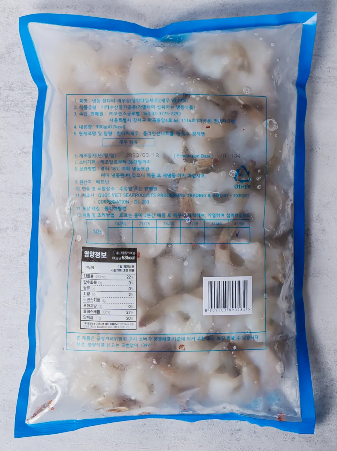 생칵테일 새우 900g 후면 백라벨 한글표시사항 이미지. 식품의 유형 수산물가공품(가열하여 섭취하는 냉동식품), 원산지 수입산, 총 내용량 900g, 영하 18도 이하 냉동 보관법, 해동 후 재냉동 금지 주의사항 및 핵심 원재료 스펙 정보가 포함된 고시 문구.