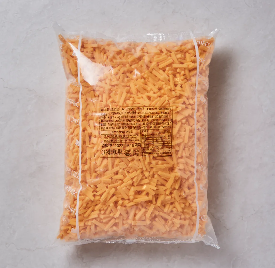 DK 슈레드 체다치즈 2.5kg 대용량 투명 비닐 패키지에 가득 담긴 주황색 체다치즈 실물 이미지